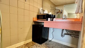A bathroom with a tiled floor, a sink with a pink countertop, a black refrigerator, and a mirror above the sink. - Downtown CF Studio - Free Gated Parking! 516 (Cedar Falls)