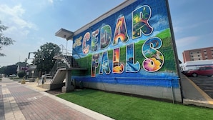 A wall with a colorful mural advertising Cedar Falls. - Downtown CF Studio - Free Gated Parking! 516 (Cedar Falls)