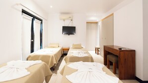 Een hotelkamer met twee bedden, een televisie, een houten bureau en een massagetafel.