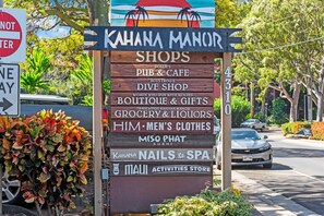 A signboard listing various shops and services including a pub, dive shop, boutique, grocery, and spa. - Amazing Stay - 2 Bed Maui Condo! (Lahaina)