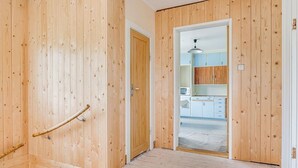 Een kamer met houten wanden, een deur en uitzicht op een keuken.