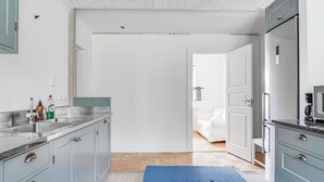 Een moderne keuken met grijze kastjes, een roestvrijstalen spoelbak en een blauw vloerkleed.