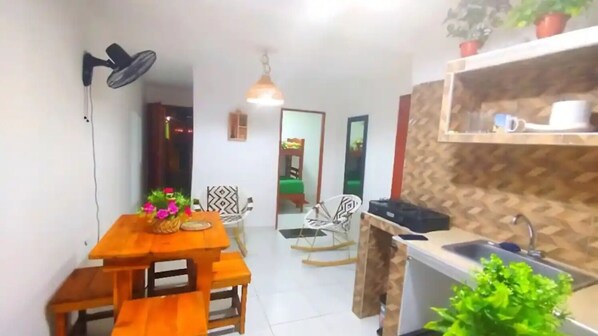 Cozy living space with a dining area, kitchenette, and potted plants.