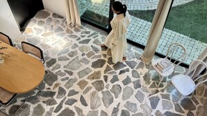 A room with a stone floor, a wooden table, and a view of a paved area outside. - Atelier Lumi - @_lumicollection (Miami)