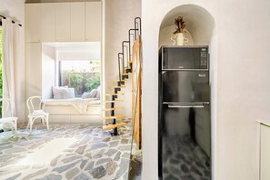 A modern kitchen with a black refrigerator, a stone-tiled floor, and a built-in bench with cushions. - Atelier Lumi @_lumicollection (Miami)