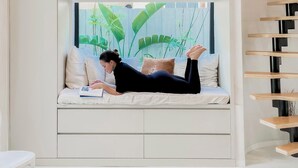 A room with a built-in bench, a window with a view of plants, and a wooden staircase. - Atelier Lumi - @_lumicollection (Miami)