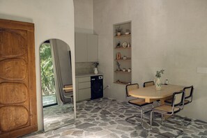 A compact kitchen with a built-in washing machine, a dining table with chairs, and a shelf with decorative items. - Atelier Lumi - @_lumicollection (Miami)