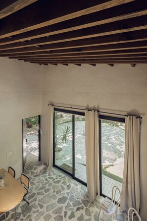 A room with a stone floor, a table with chairs, and large windows with curtains. - Atelier Lumi - @_lumicollection (Miami)