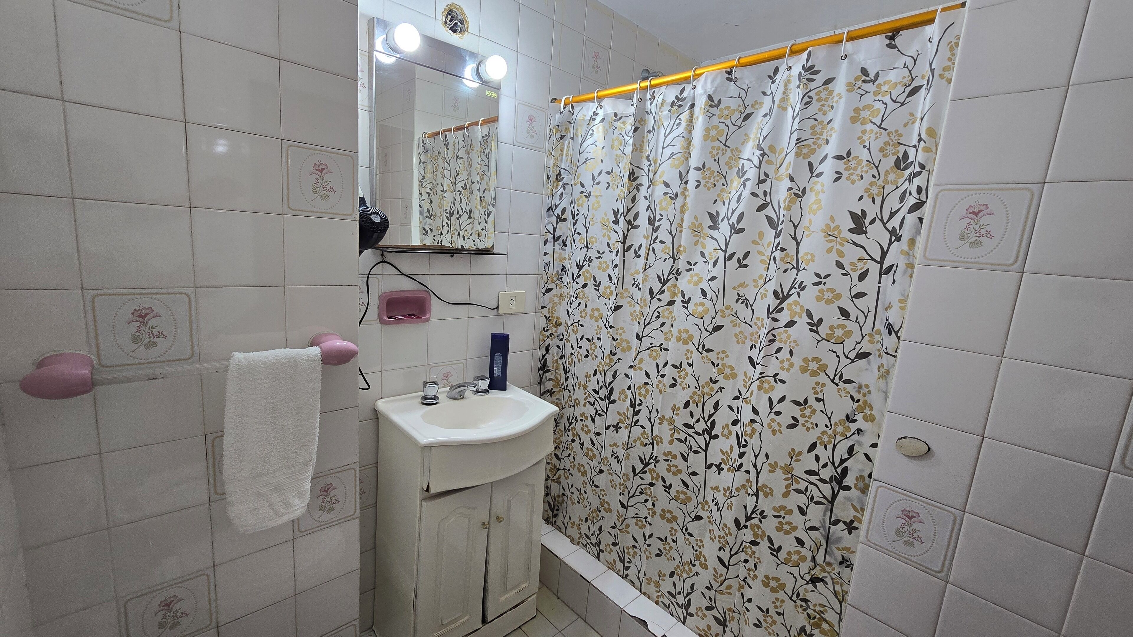 A bathroom with a white sink, a mirror, and a shower curtain with a floral pattern.