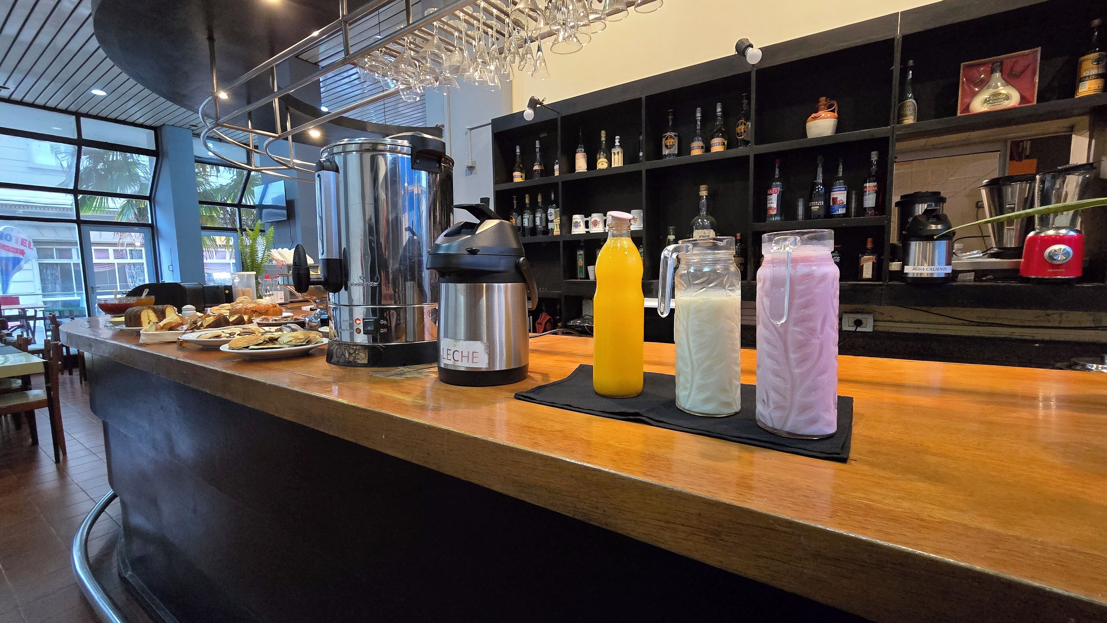 Un espace bar équipé d’une machine à café, d’un assortiment de boissons et de différentes bouteilles exposées sur des étagères.