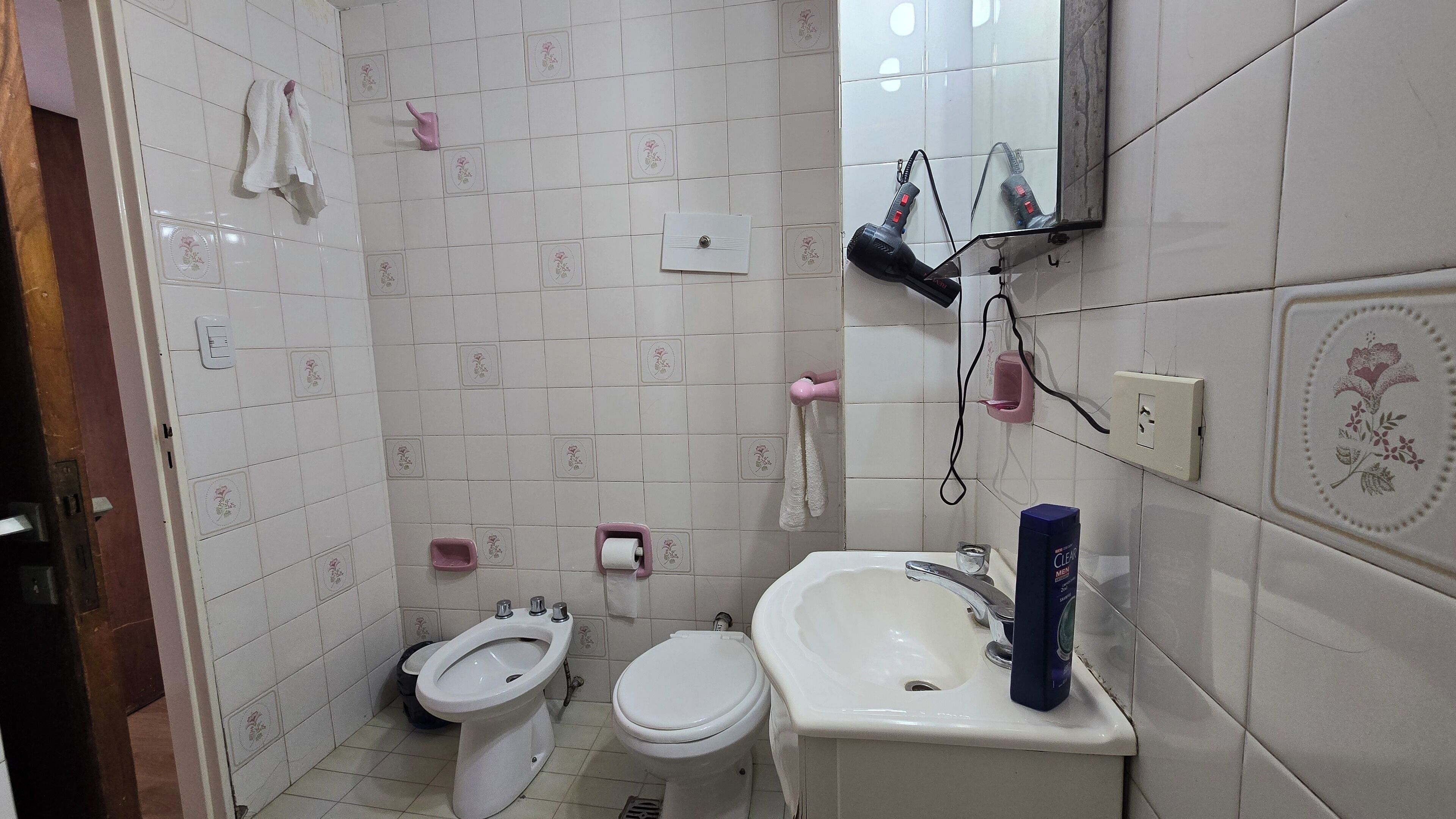 A bathroom with a toilet, bidet, sink, and a mirror.