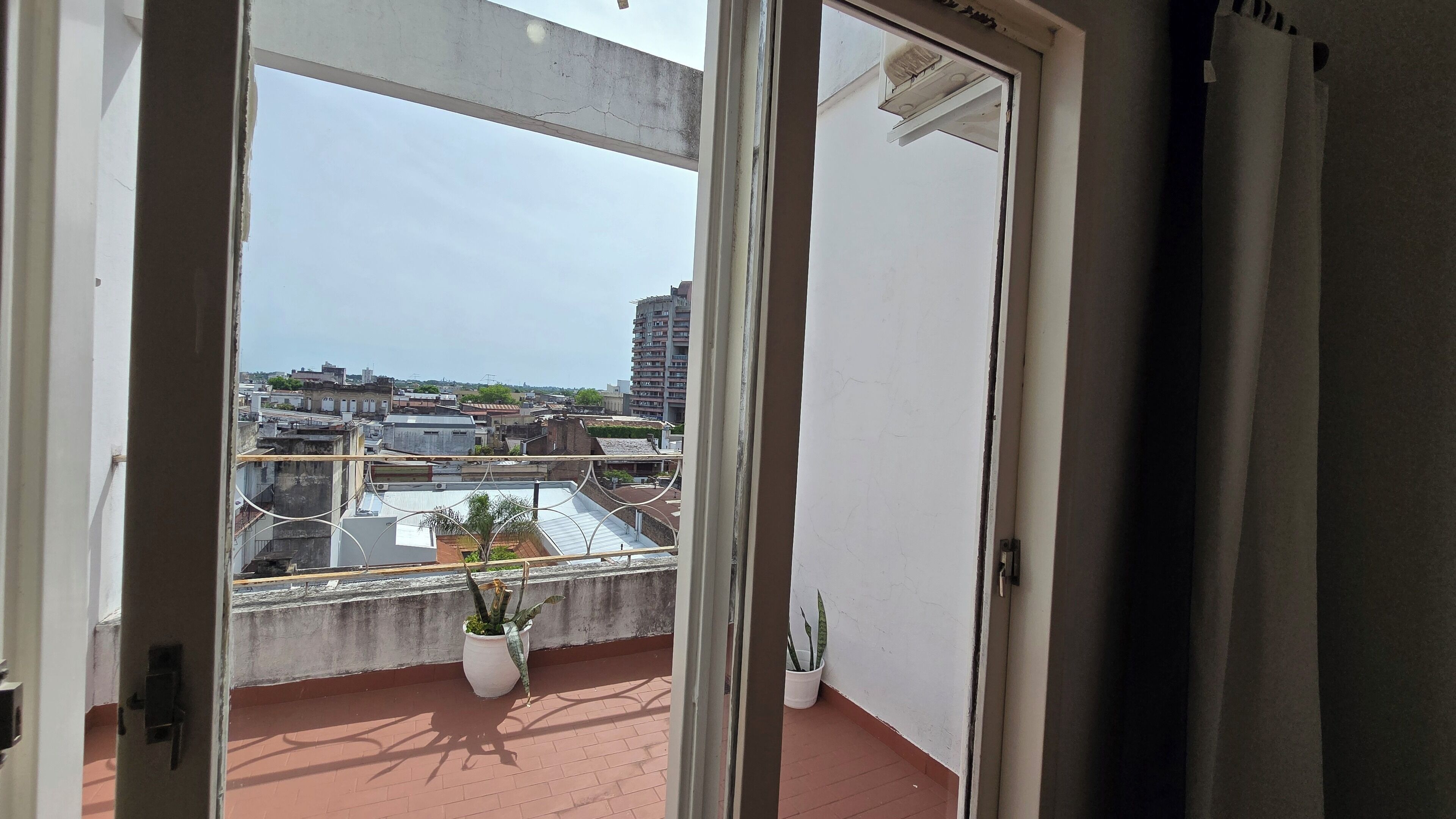 A balcony with a view of a cityscape, including buildings and a clear sky.