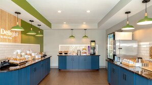 Una cucina moderna con mobili blu, un'isola centrale e lampade a sospensione verdi.