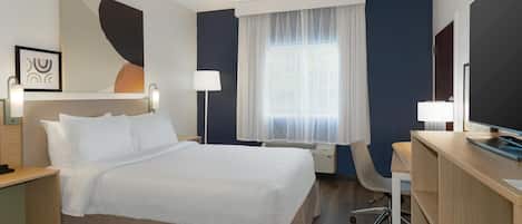Ein Hotelzimmer mit Bett, Schreibtisch, Stuhl und Fernseher.