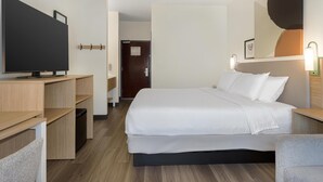 Una camera d'albergo con un letto, una TV, una scrivania e una sedia.
