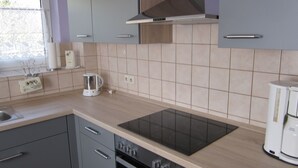 Eine moderne Küche mit grauen Schränken, einer schwarzen Induktionskochplatte und einem eingebauten Backofen.