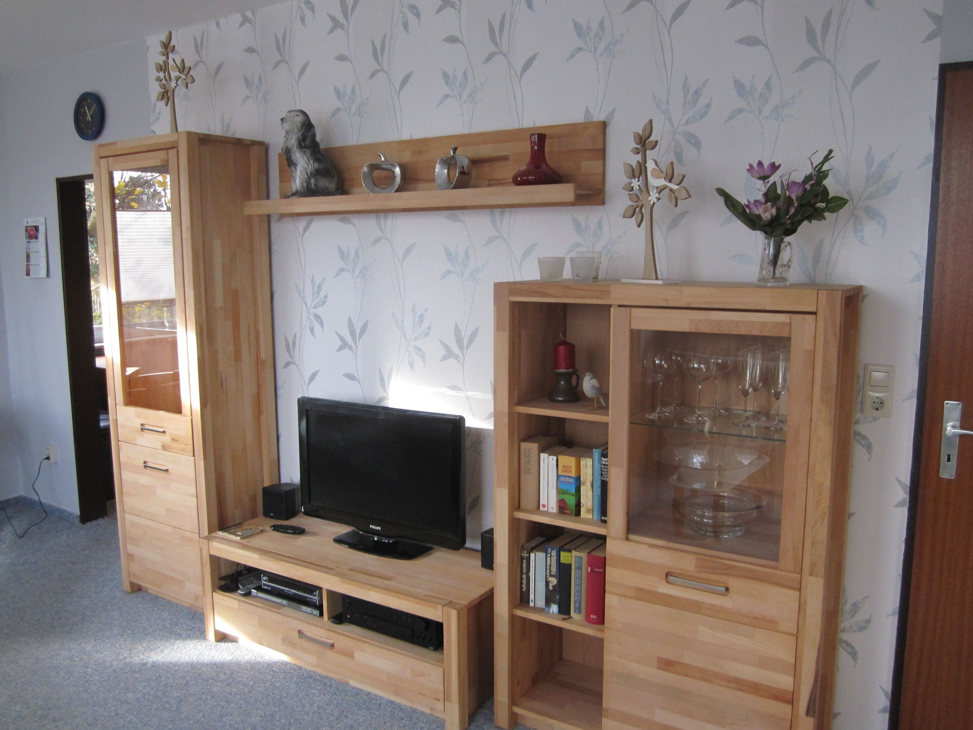 A living room with a wooden entertainment unit, a flat-screen TV, and a bookshelf.