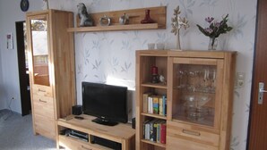 Ein Wohnzimmer mit einer Holzeinrichtungsanlage, einem Flachbildfernseher und einem Bücherregal.