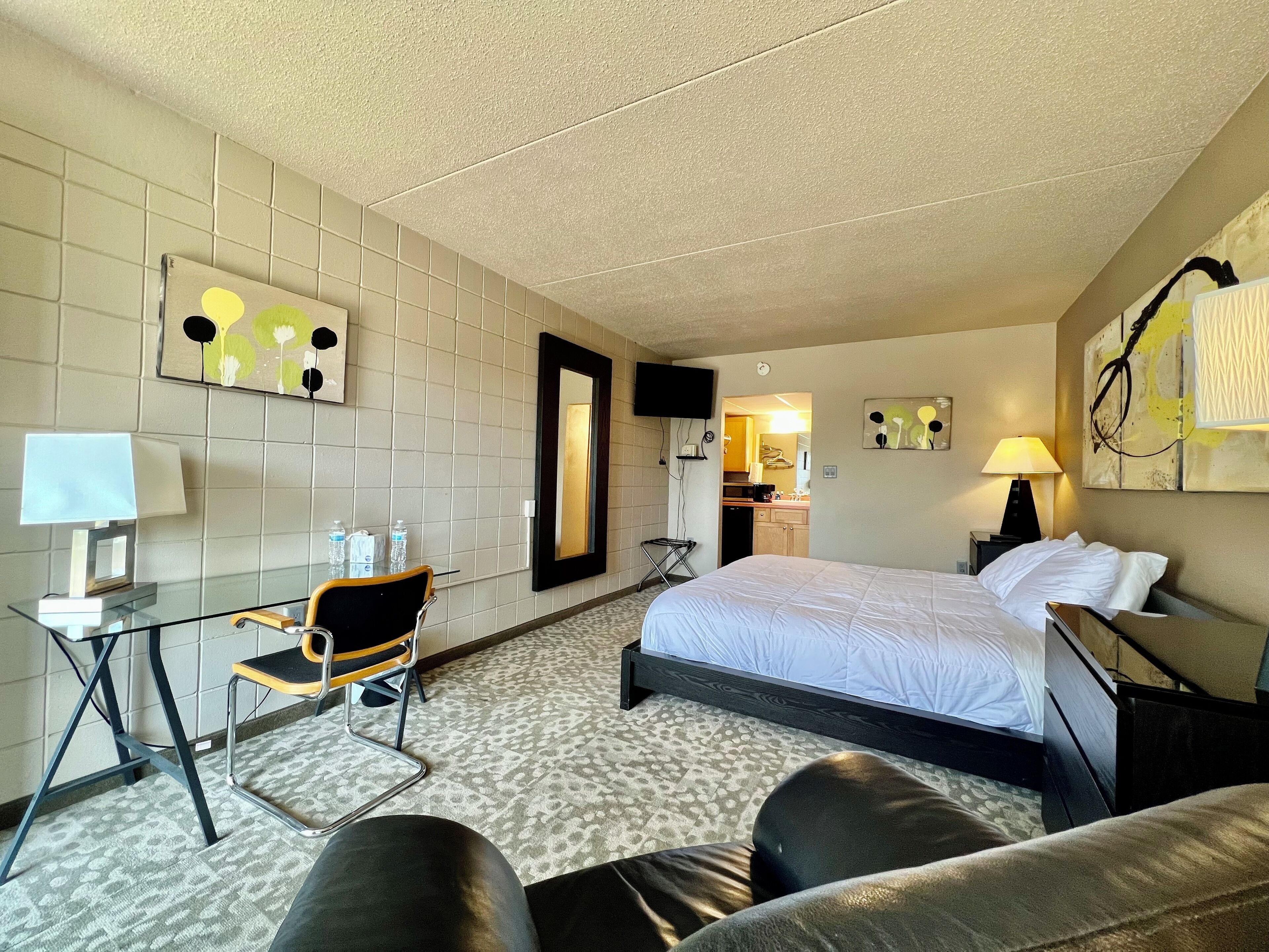 Une chambre d’hôtel avec un lit, un bureau et une chaise, une télévision et une salle de bain visible à travers une porte ouverte.