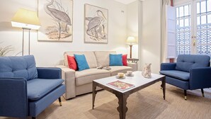 A living room with a sofa, two armchairs, a coffee table, and wall art. - Genteel Home San Isidoro II (Seville)