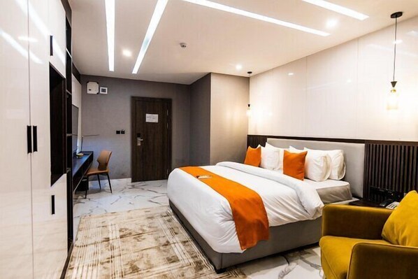 A modern hotel room with a large bed, a desk, and a chair.