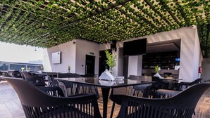 A rooftop bar with black chairs and a table, surrounded by greenery and a modern design. - Bon Hotel Boutique Garki 2 (Abuja)