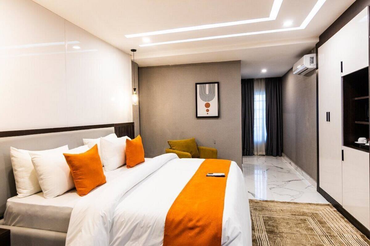 A modern hotel room with a large bed, a desk, and a wardrobe.