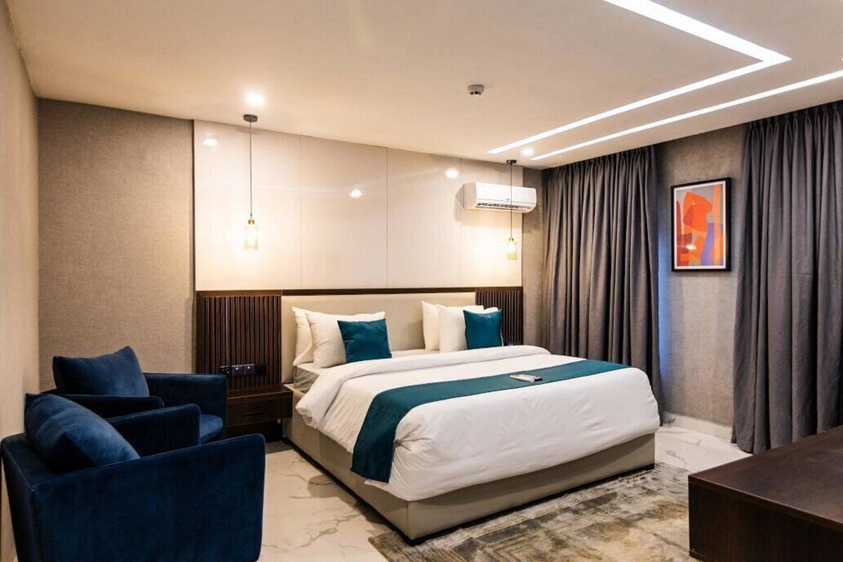 A modern hotel room with a large bed, a desk, and a seating area.