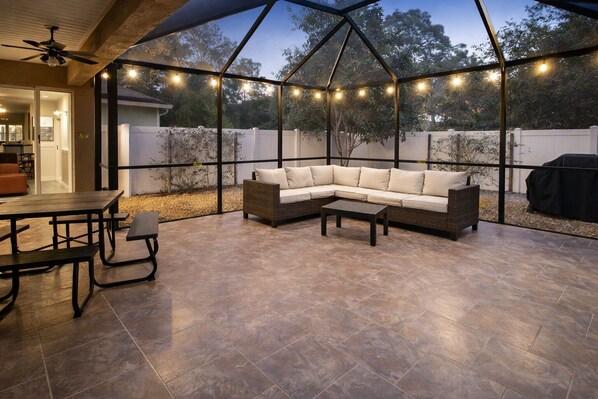 Eine Terrasse im Freien mit einer Eckcouch, einem Esstisch mit Stühlen und Lichterketten.