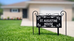 Skilt med 'St. Augustine House' på en græsplæne.