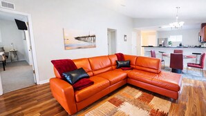 En moderne stue med en hjørnesofa, spiseplads og et køkken.