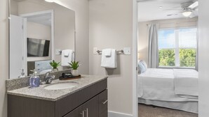 Un bagno moderno con un piano di lavoro in granito, un lavandino, uno specchio e una ventola a soffitto.