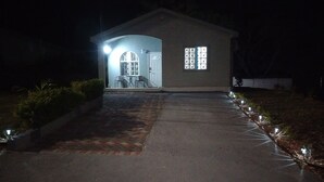 Un edificio con ingresso lastricato, un piccolo patio con sedie e una finestra con persiane a griglia.
