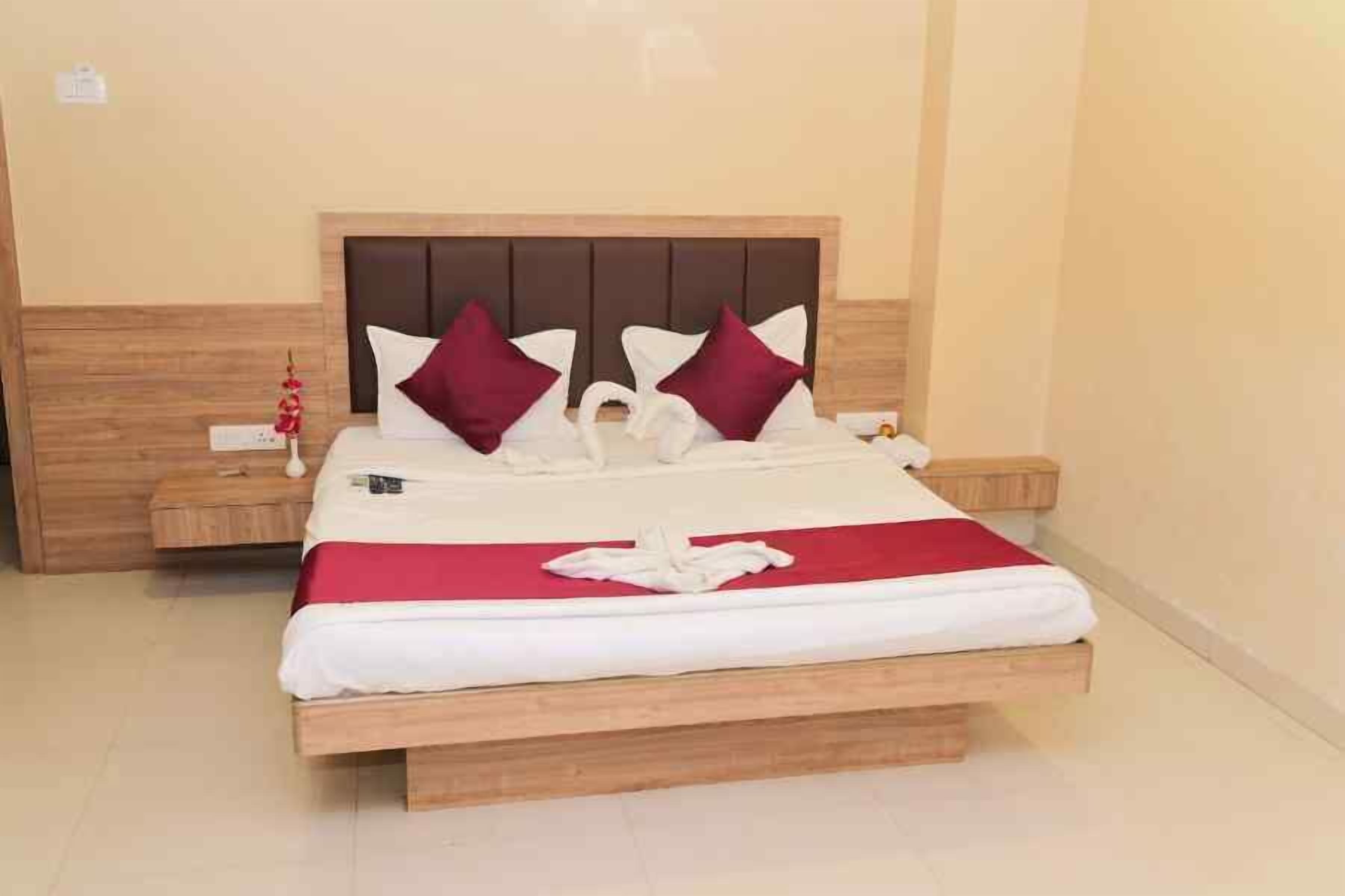 A neatly made bed with a wooden headboard, white and red bedding, and a decorative swan pillow arrangement.