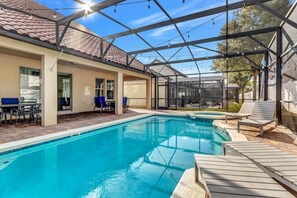 A swimming pool with lounge chairs and a covered patio area. - 5 bed with spa and games room (Davenport)