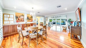 A spacious kitchen with wooden cabinets, a dining table with chairs, and a chandelier.