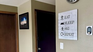 Ein Zimmer mit Holzboden, einer Tür, einer Wanduhr, einem gerahmten Bild und einem motivierenden Schild.