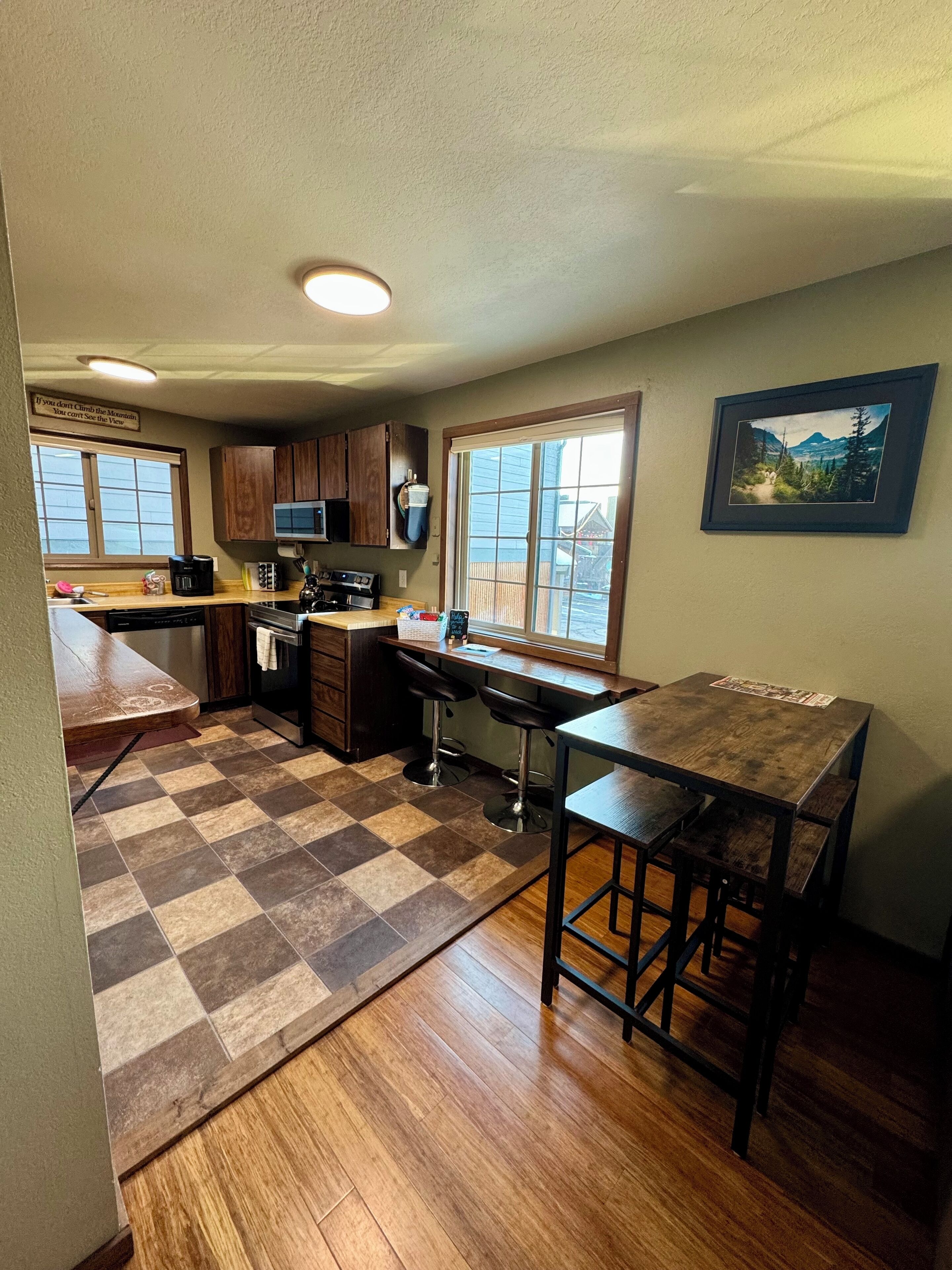 A kitchen with wooden cabinets, a microwave, a coffee maker, and a large window.
