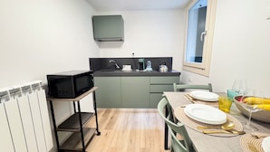 A compact kitchen with a microwave on a shelf, a sink, and a dining area with a table set for two.