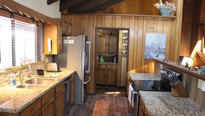 Eine Küche mit Holzausstattung, Granit Arbeitsplatten, einem Kühlschrank, einem Herd und einer Spüle.