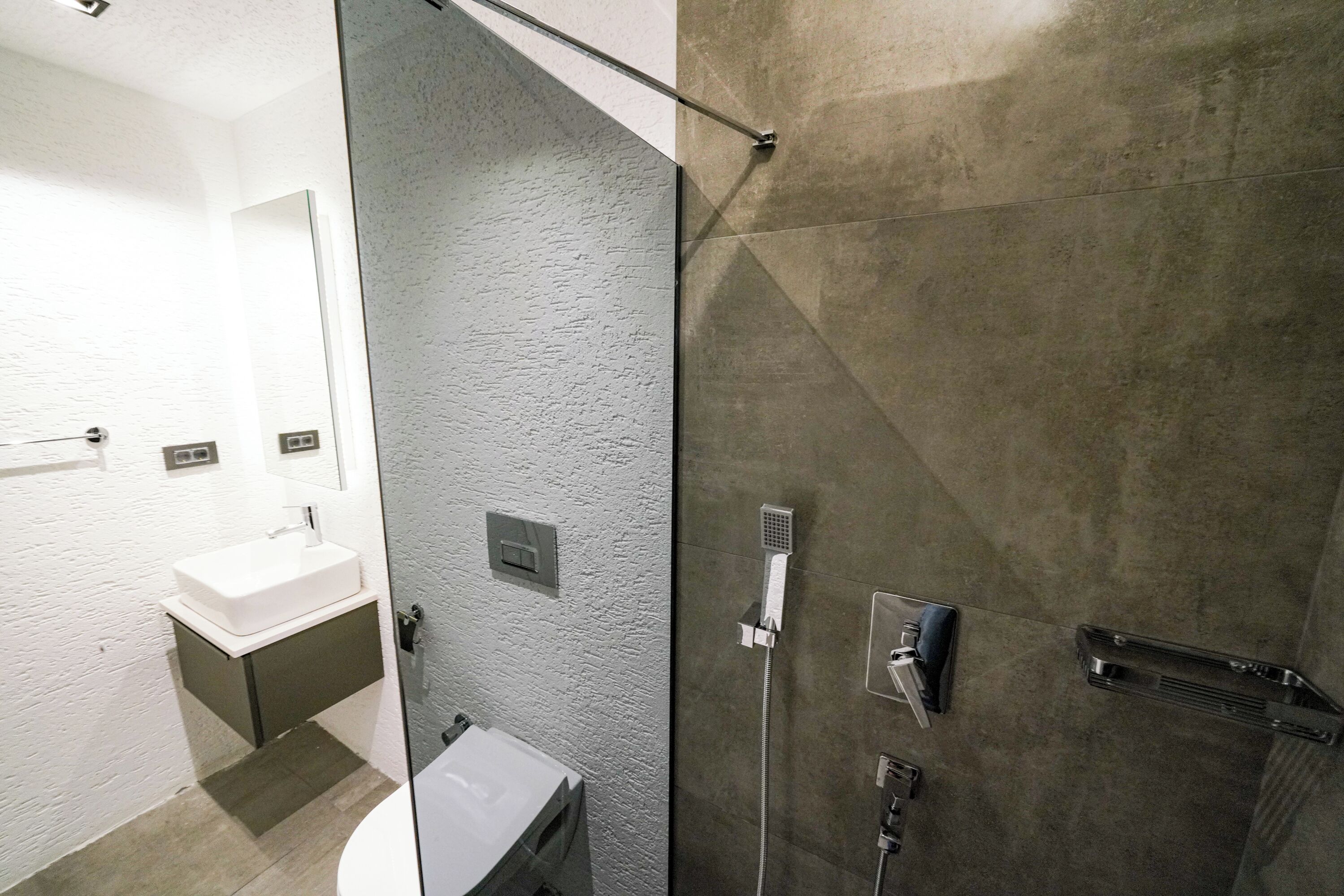 Un baño moderno con mampara de vidrio, un lavabo blanco y zona de ducha.