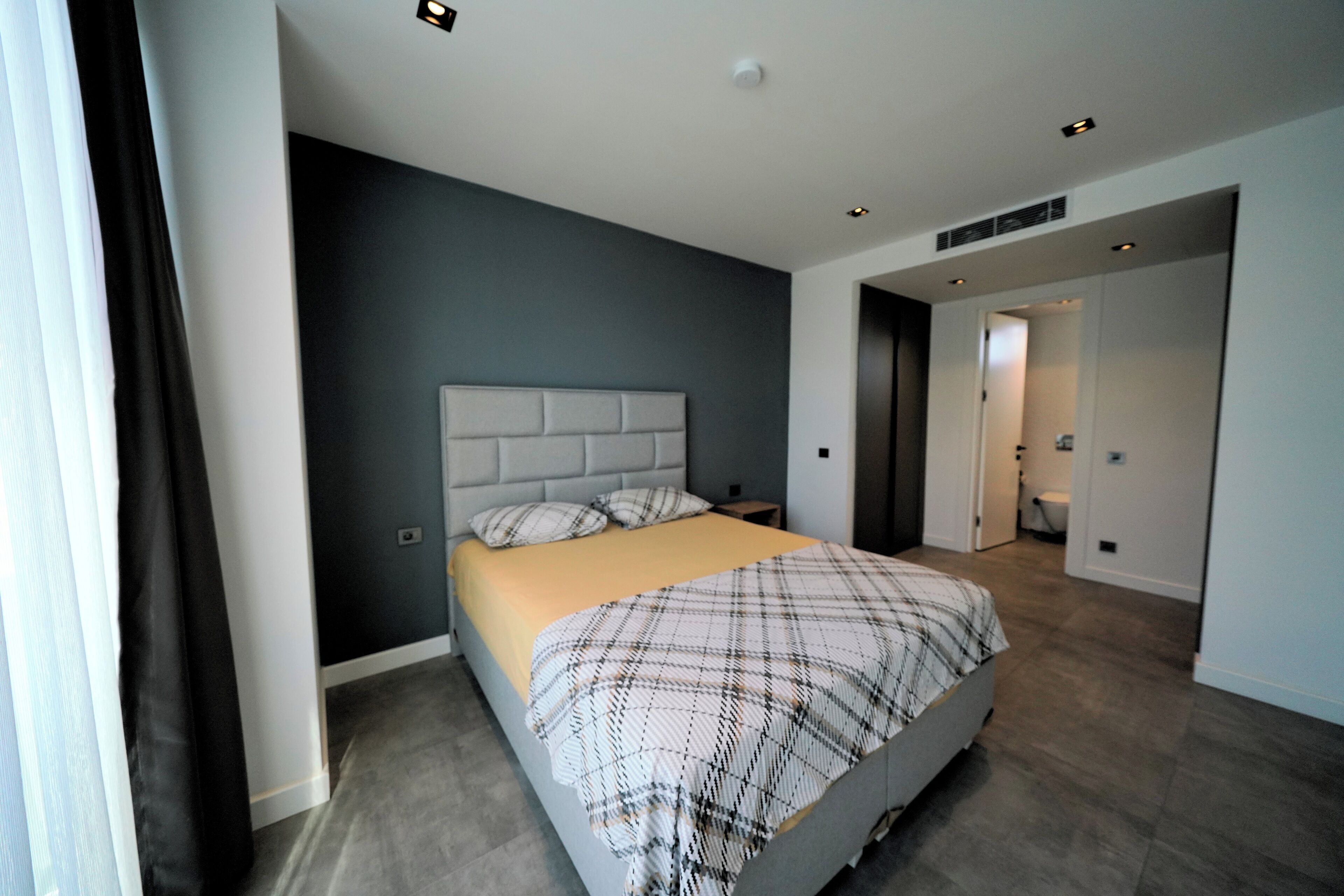 Une chambre à coucher moderne avec un grand lit, une tête de lit et une table de chevet.