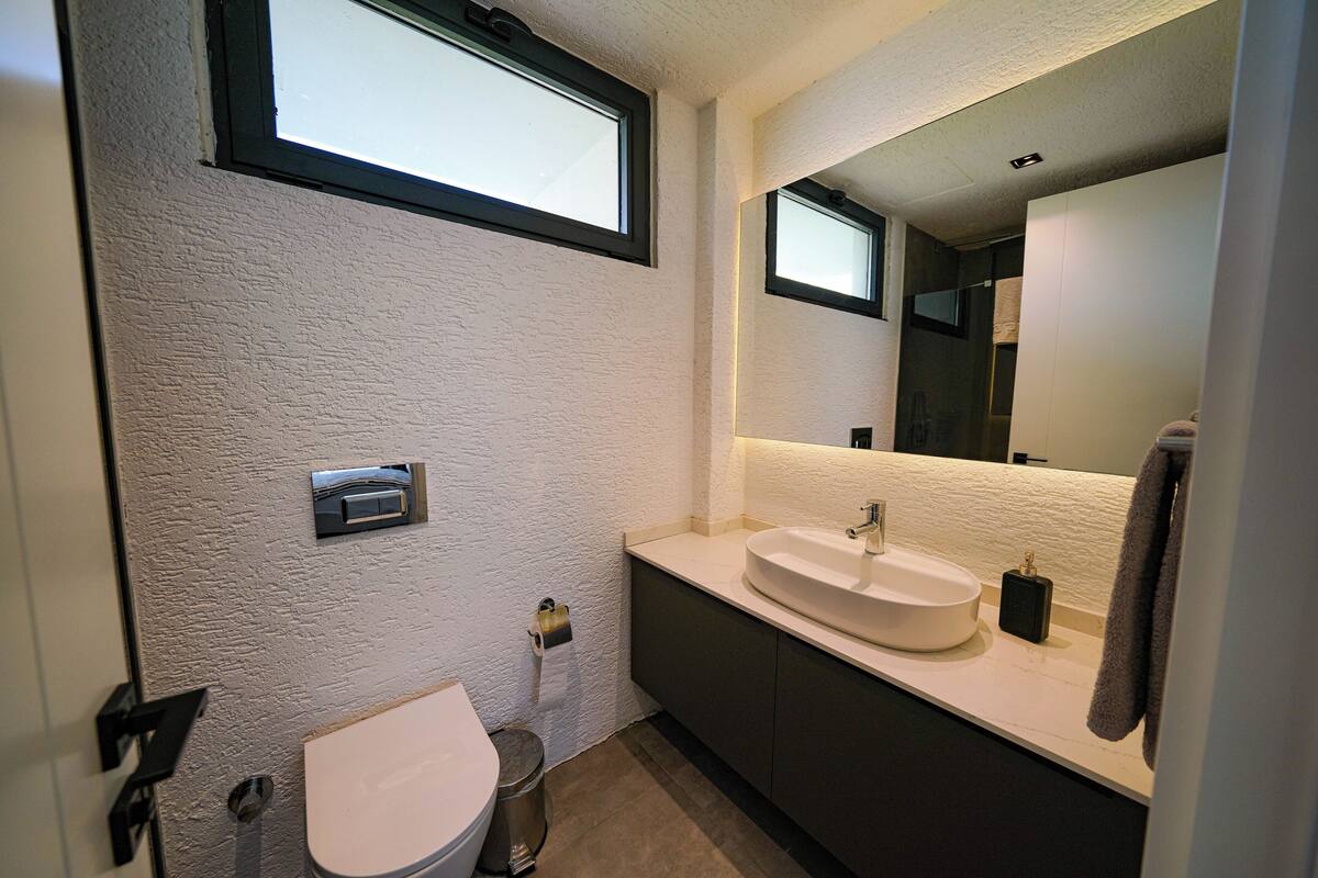 A bathroom with a toilet, sink, and mirror.