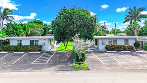 Un motel composé de bâtiments à deux étages, d’un parking et d’un grand arbre situé au centre.