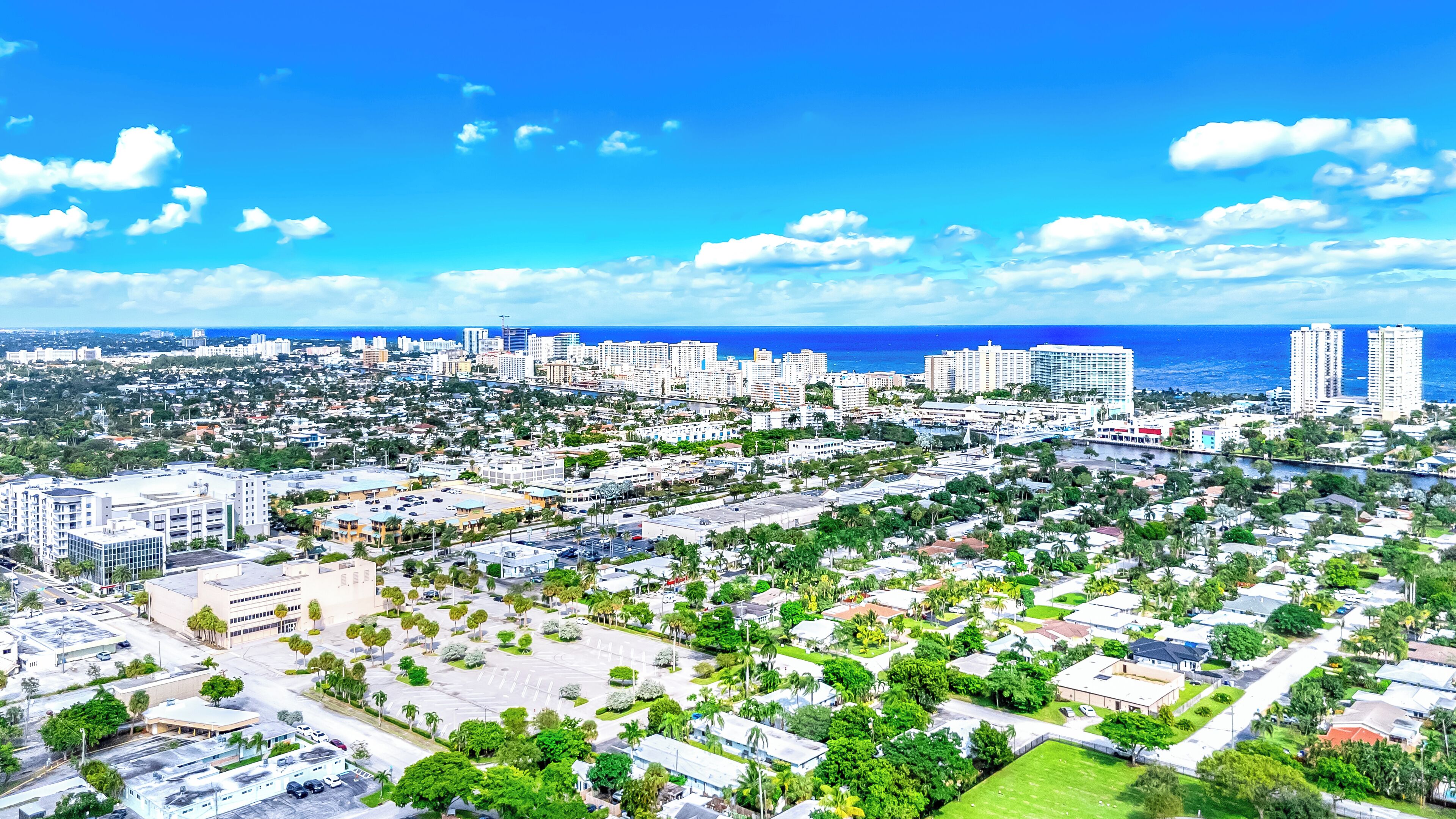 An aerial view of a coastal city with dense urban development, including high-rise buildings and a marina.