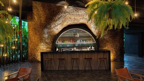 Eine Bar mit einer Steinwand, Holzstühlen und einer Auswahl an Flaschen und Gläsern in den Regalen.