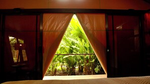 A room with a bed, a window, and a view of a garden.