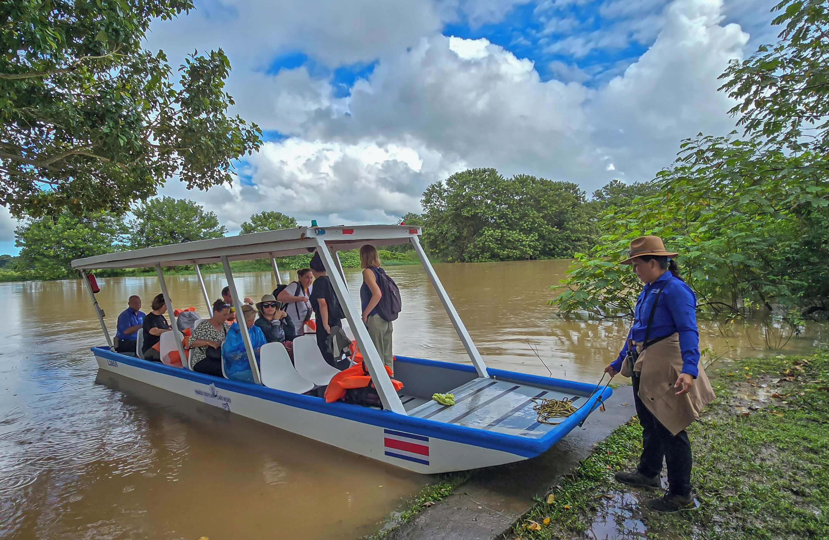 Un bateau transportant des passagers, avec un guide debout sur la rive.
