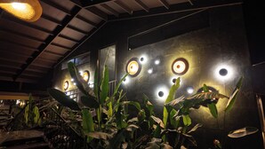 A modern interior with a high ceiling, industrial-style lighting, and a wall adorned with circular light fixtures.