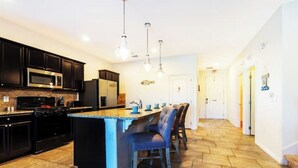 A modern kitchen with dark cabinets, a central island, and pendant lighting. - 5 bdrm5, ensuites, Pool, free Grill, Solterra4695

 (Davenport)